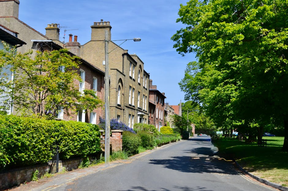 A narrow residential street in Hornchurch with closely spaced terraced houses on both sides, parked cars lining the curb, including a small flatbed vehicle with open sides positioned on the left side